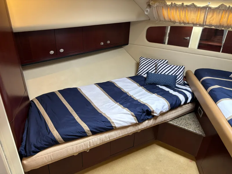 Slide: The Image of 2006 Sea Ray 40 Motor Yacht cabin with striped bedding and wooden cabinets. - 21