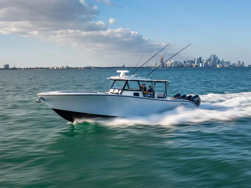Slide: The Image of 2024 Yellowfin 42 boat cruising on open water with city skyline in background. - 0