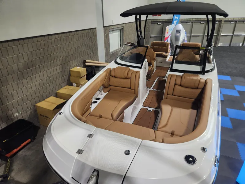 Slide: The Image of 2025 Hurricane SunDeck 2600 OB boat with tan seating and black canopy in showroom. - 2