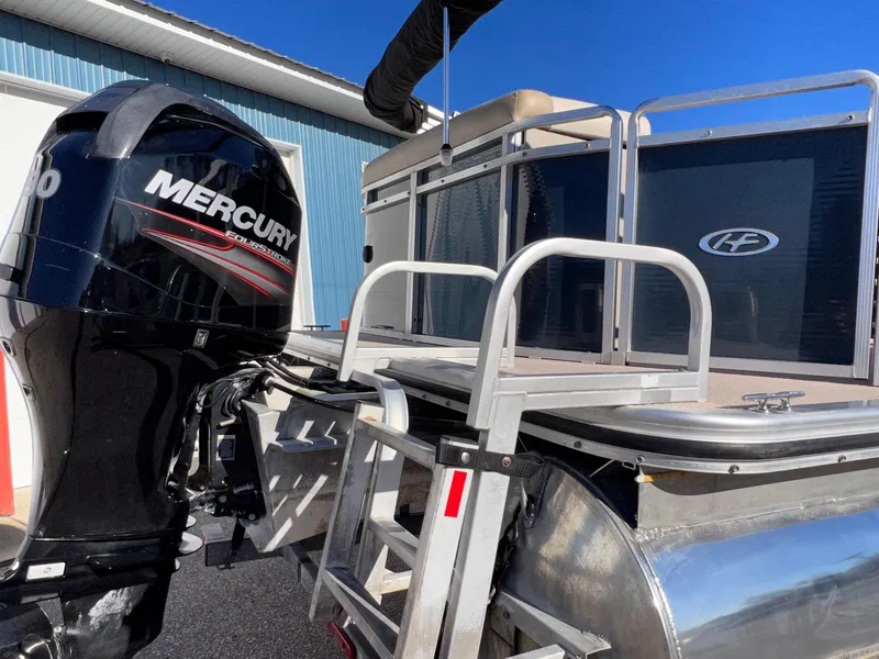 Slide: The Image of 2013 Harris FloteBote Cruiser with Mercury outboard motor, docked under clear blue sky. - 4