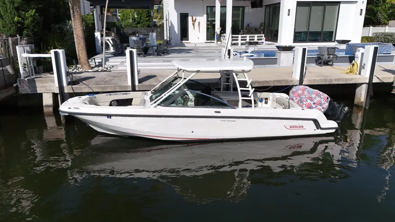 Slide: The Image of 2014 Boston Whaler 270 Vantage boat docked by a modern waterfront home. - 0