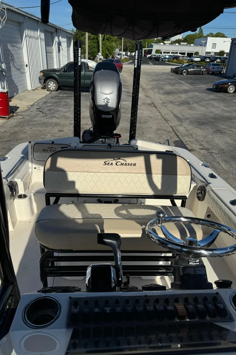 Slide: The Image of 2021 Sea Chaser 26LX boat interior with steering wheel and seating, parked outdoors. - 35