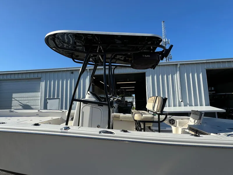 Slide: The Image of 2021 Sea Chaser 26LX boat with T-top, docked near a warehouse under clear blue sky. - 4