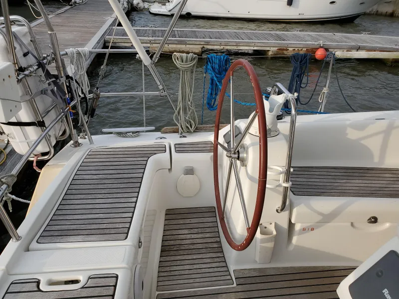 Slide: The Image of Beneteau 43 sailboat cockpit with wooden deck and steering wheel, docked at marina. - 14
