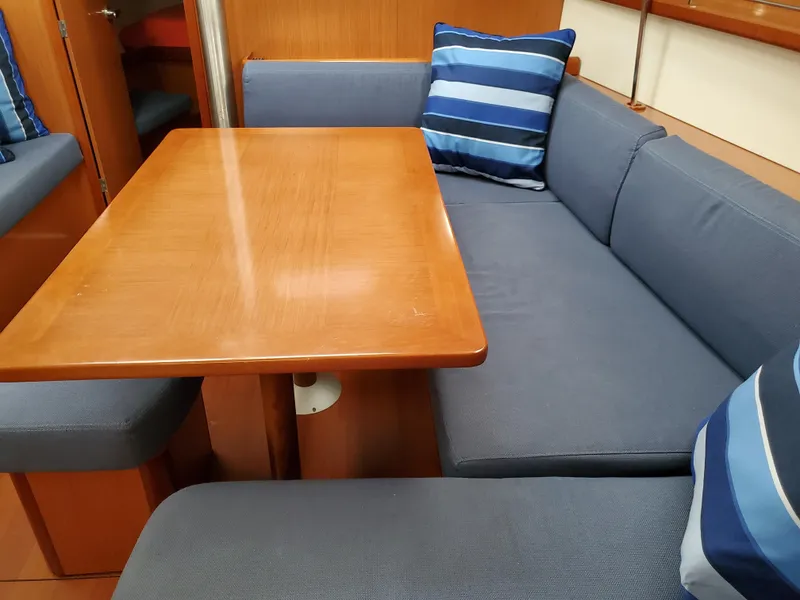 Slide: The Image of Beneteau 43 (2008) yacht interior with blue cushioned seating and wooden table. - 38