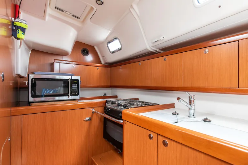 Slide: The Image of 2008 Beneteau 43 yacht kitchen with wood cabinets, stove, and microwave. - 42
