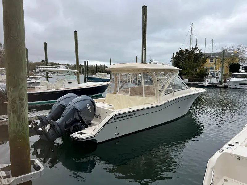 Slide: The Image of 2022 Grady-White Freedom 325 boat docked in a marina with twin outboard engines. - 1