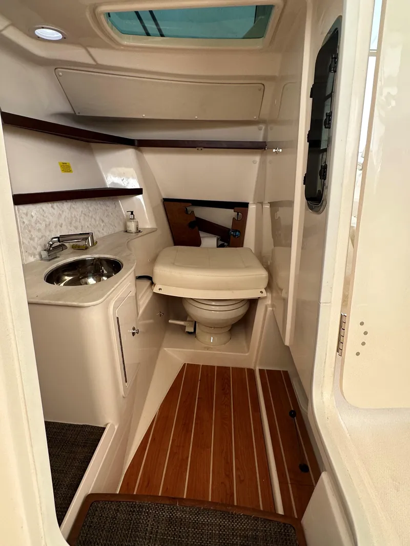Slide: The Image of 2022 Grady-White Freedom 325 boat interior with compact bathroom and wooden flooring. - 14