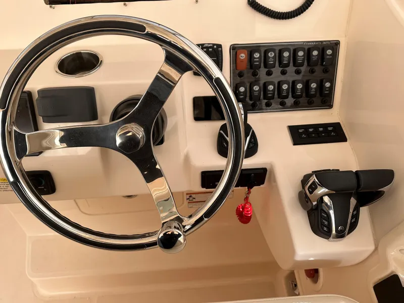 Slide: The Image of 2022 Grady-White Freedom 325 boat dashboard with steering wheel and control panel. - 2