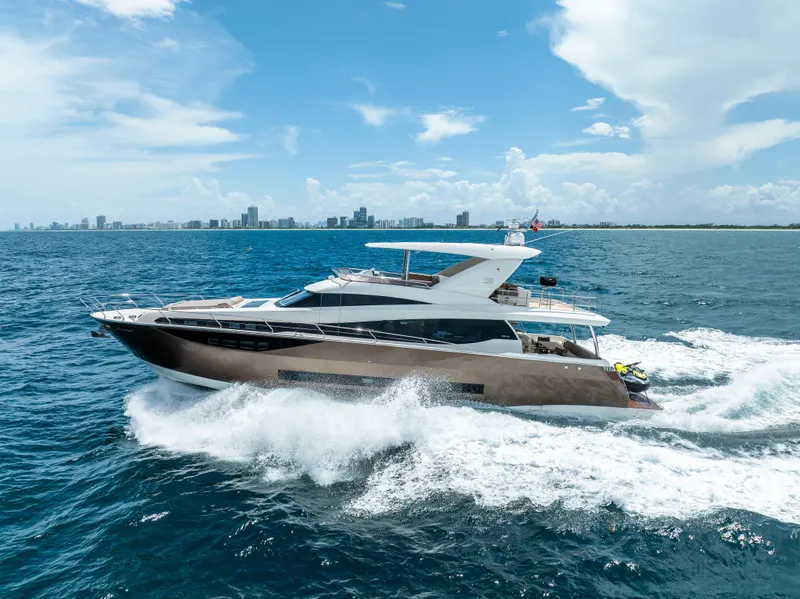 Slide: The Image of Luxury 2015 Prestige 750 yacht cruising on open sea with city skyline backdrop. - 1