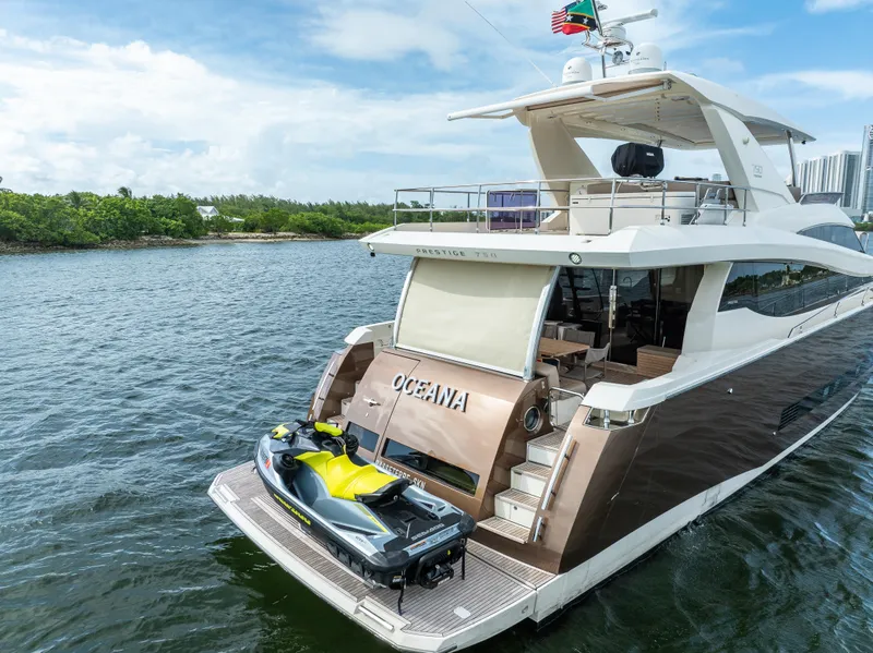 Slide: The Image of Prestige 750 yacht from 2015 with jet ski on deck, cruising in scenic waters. - 15