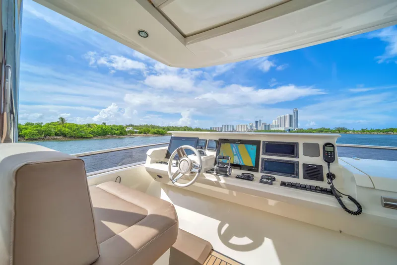 Slide: The Image of Prestige 750 yacht helm with modern controls, overlooking scenic waterfront skyline. - 27