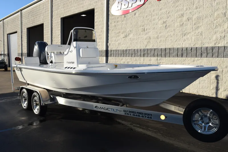 Slide: The Image of 2025 Frontier 2104 boat on trailer, parked outside a building. - 2