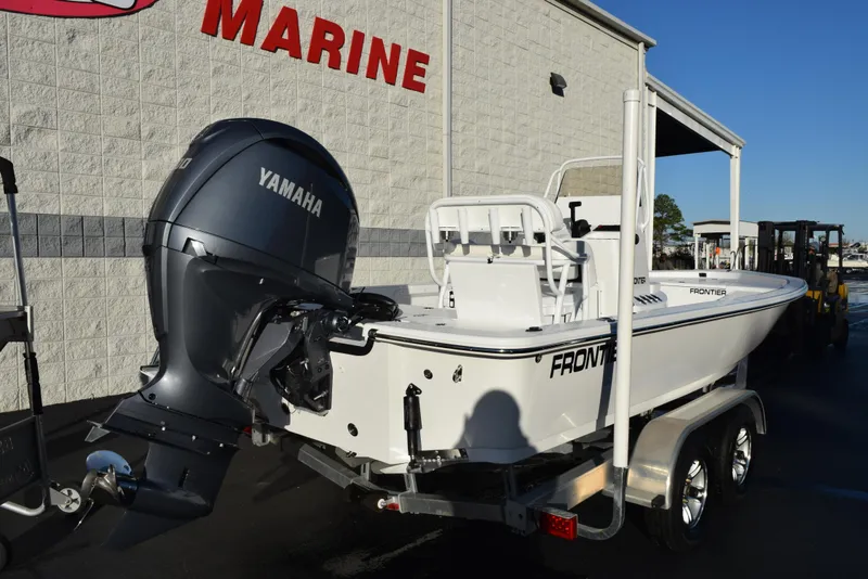 Slide: The Image of Frontier 2104 boat with Yamaha engine on trailer, parked outside marine store. - 4