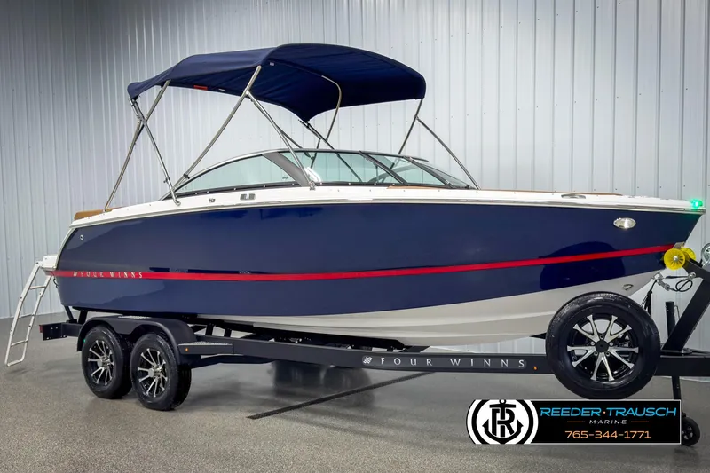 Slide: The Image of 2025 Four Winns H2 boat with blue hull and canopy on a trailer in a showroom. - 3