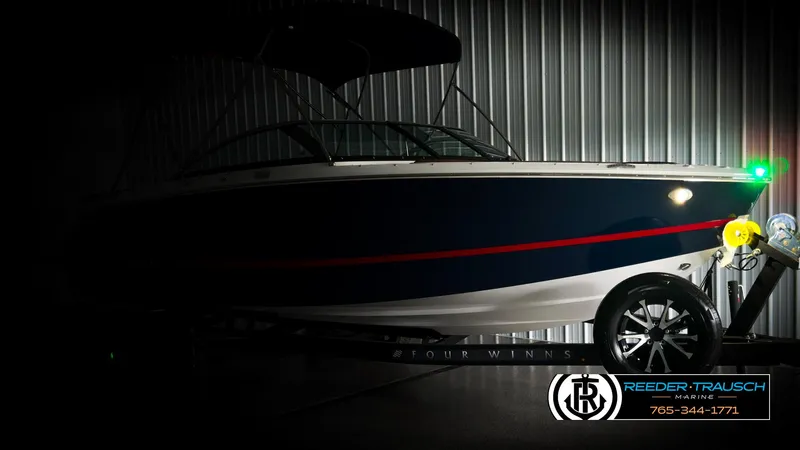 Slide: The Image of 2025 Four Winns H2 boat in a dimly lit showroom, side view with trailer. - 4