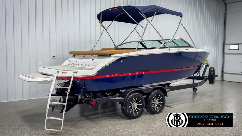 Slide: The Image of 2025 Four Winns H2 boat on trailer in showroom with canopy and swim platform. - 6