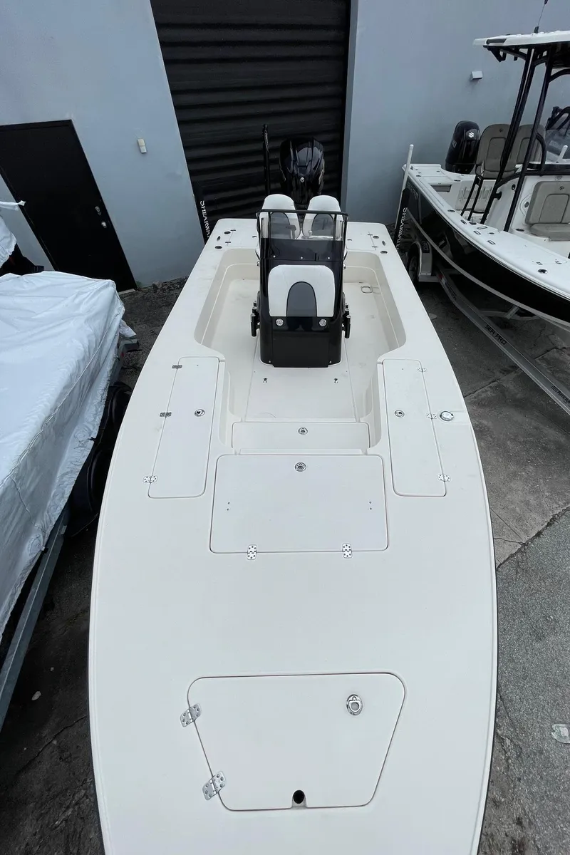 Slide: The Image of 2024 ShearWater X22 boat, sleek design, white deck, dual seats, parked in a marina. - 7