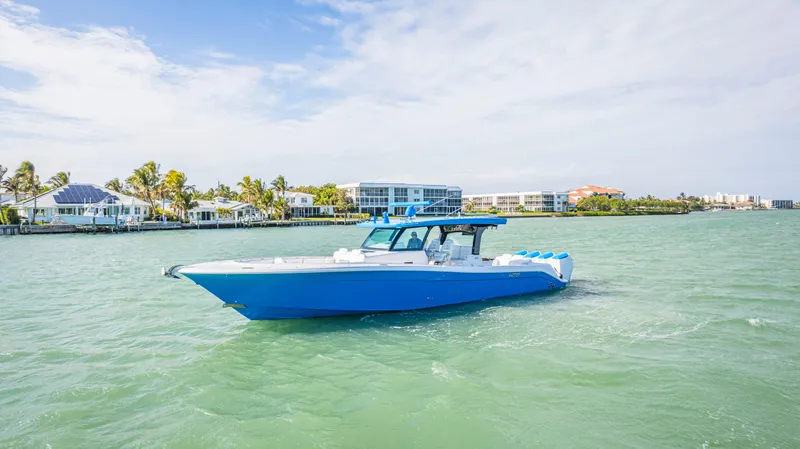Slide: The Image of 2025 HCB 48 Campeon boat cruising on a sunny day near coastal homes. - 42