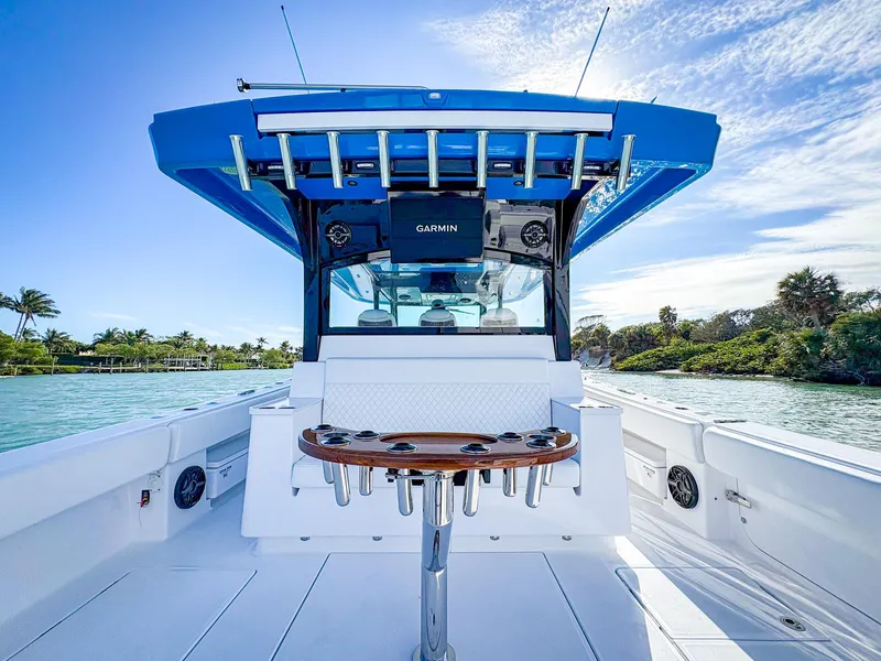 Slide: The Image of 2025 HCB 48 Campeon boat, sleek design, open deck, blue canopy, scenic waterway backdrop. - 5