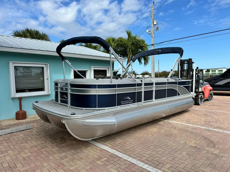 Slide: The Image of 2020 Bennington 22SSXAPG pontoon boat parked on brick driveway, blue sky background. - 1