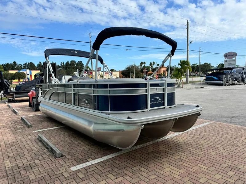 Slide: The Image of 2020 Bennington 22SSXAPG pontoon boat parked on brick pavement under a blue sky. - 3