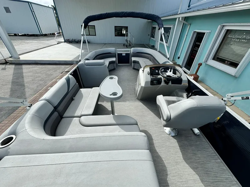 Slide: The Image of 2020 Bennington 22SSXAPG pontoon boat with spacious seating and helm, docked near a building. - 9