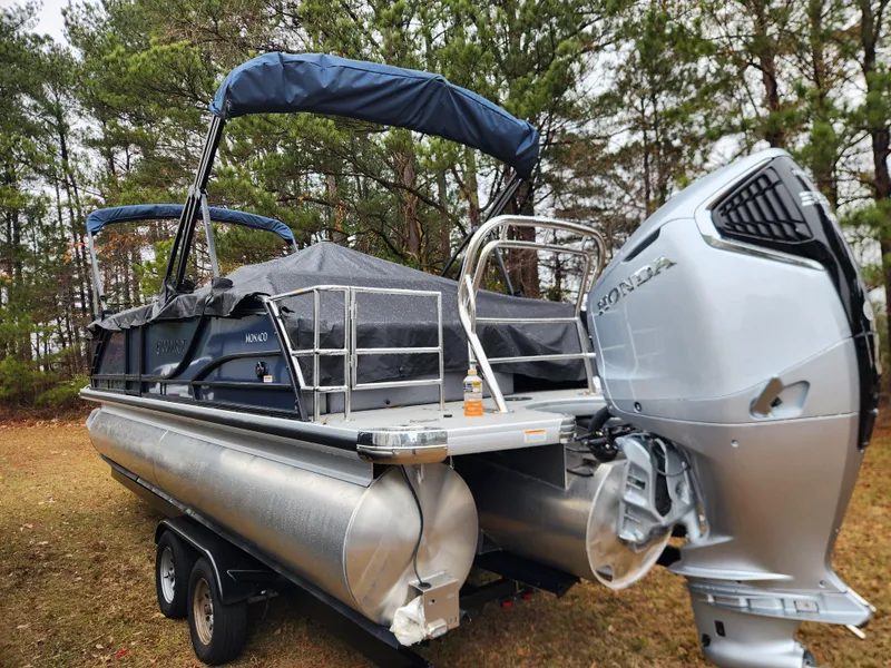 The Image of 2025 Godfrey Monaco 255 SFL pontoon boat with Honda outboard motor, parked on trailer. - 0