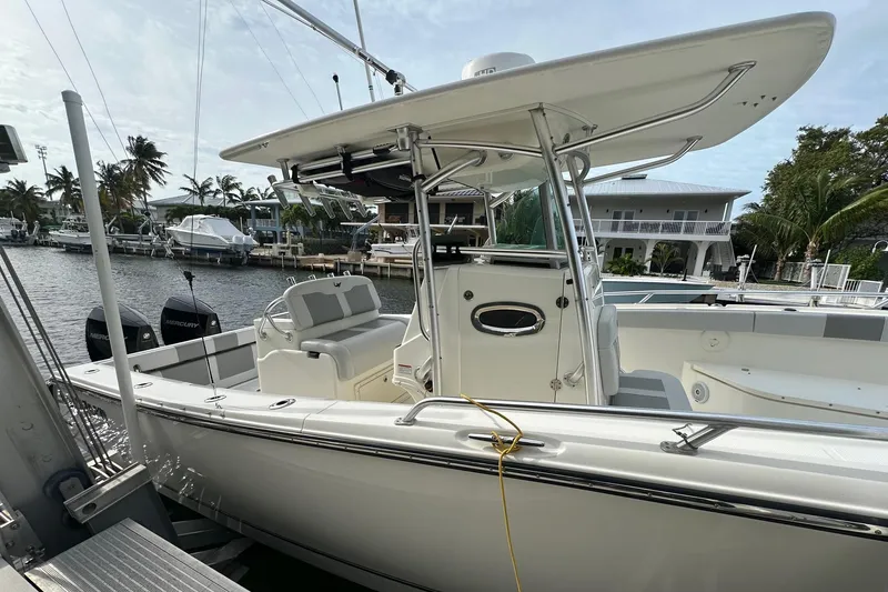 Slide: The Image of 2020 Mako 284 CC boat docked by waterfront homes, featuring sleek design and spacious deck. - 2