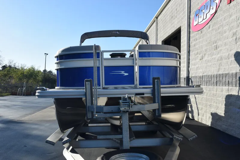 Slide: The Image of 2025 Bennington SX 24 Quad Bench pontoon boat on trailer, parked outside a building. - 3