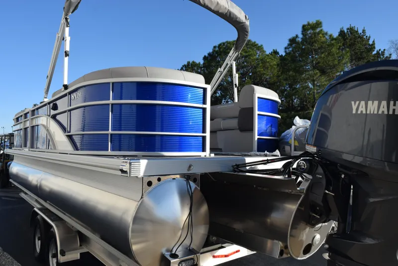 Slide: The Image of 2025 Bennington SX 24 Quad Bench pontoon boat with Yamaha motor, parked outdoors. - 6