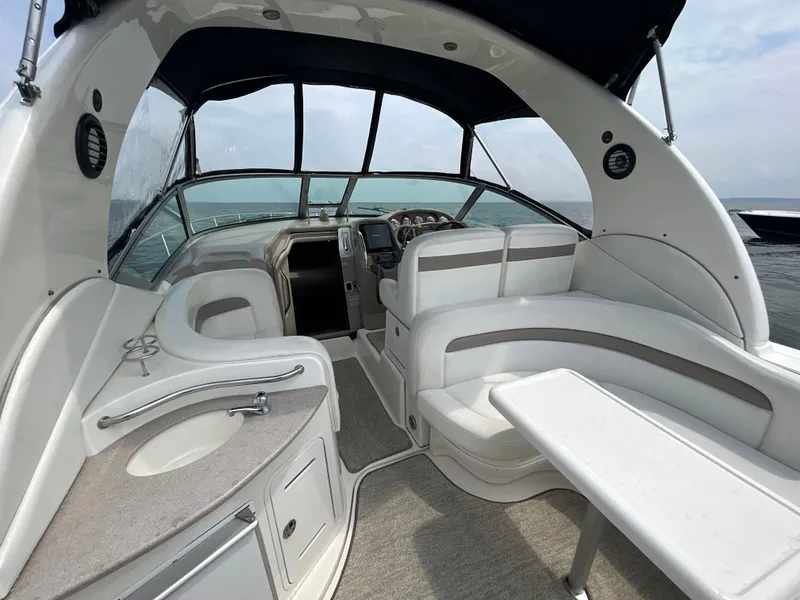 Slide: The Image of 2004 Sea Ray 320 Sundancer interior with seating, table, and helm on open water. - 10