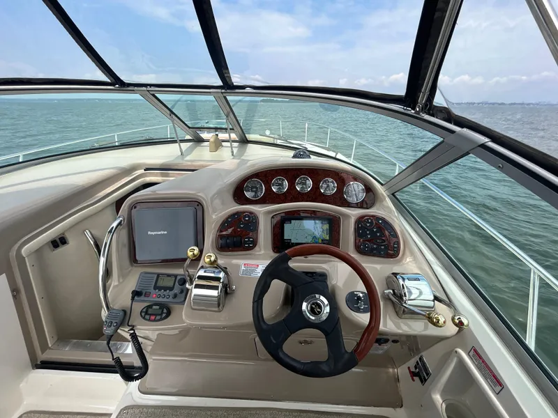 Slide: The Image of 2004 Sea Ray 320 Sundancer helm with steering wheel and navigation controls. - 11