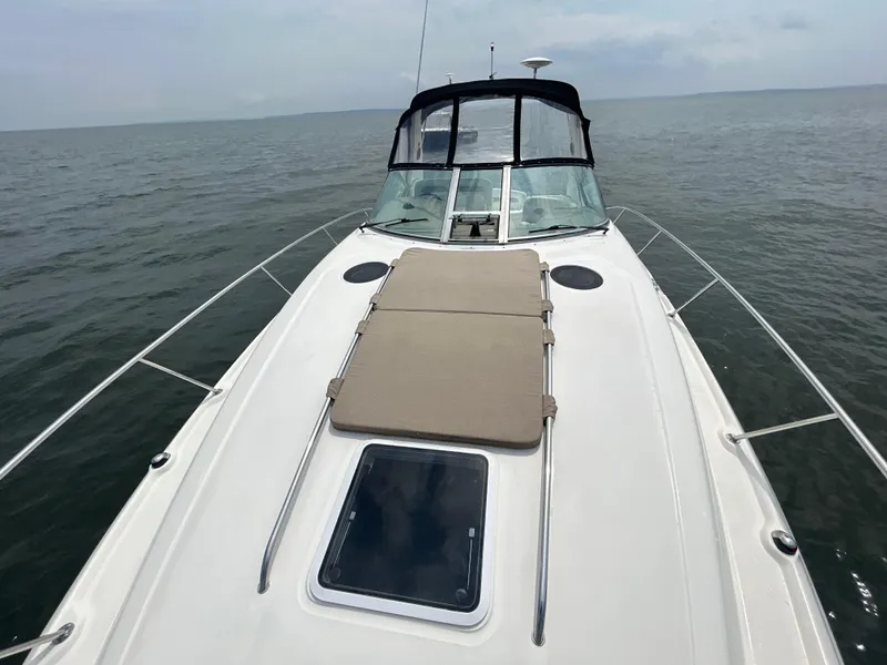 Slide: The Image of 2004 Sea Ray 320 Sundancer boat on open water, featuring a spacious deck. - 13