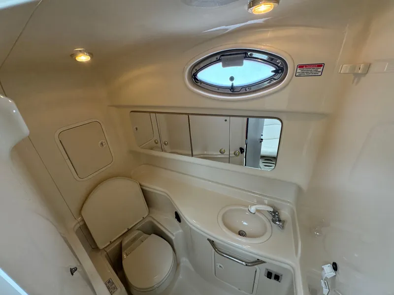 Slide: The Image of 2004 Sea Ray 320 Sundancer bathroom with sink, toilet, and mirror cabinet. - 18