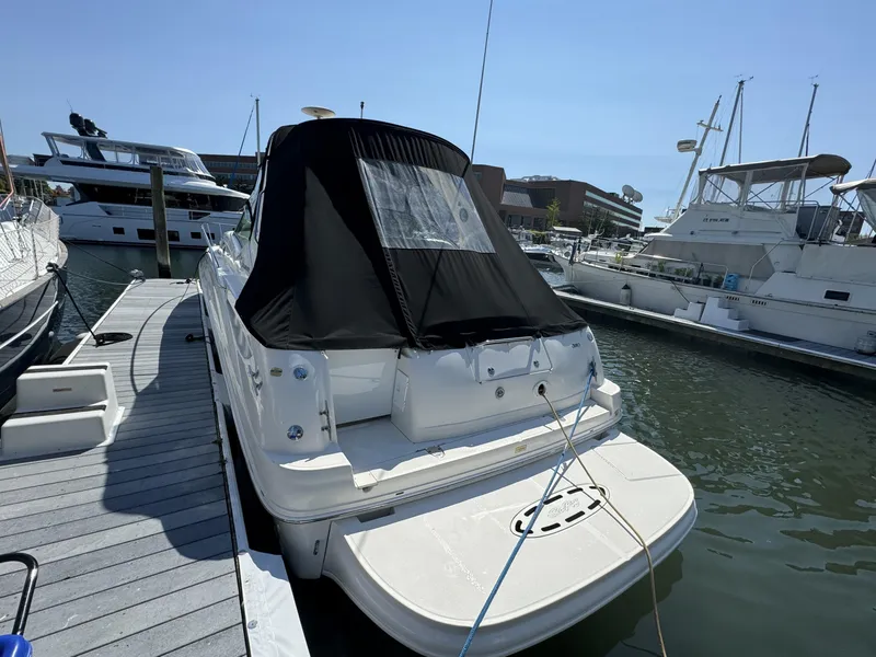 Slide: The Image of 2004 Sea Ray 320 Sundancer docked at marina, rear view with black cover. - 3
