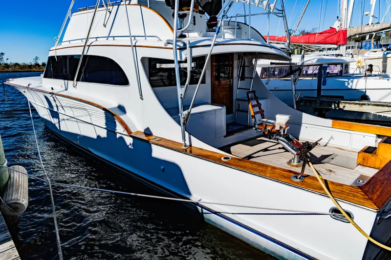 Slide: The Image of 1987 Buddy Davis 61 Convertible yacht docked, showcasing sleek design and spacious deck. - 3