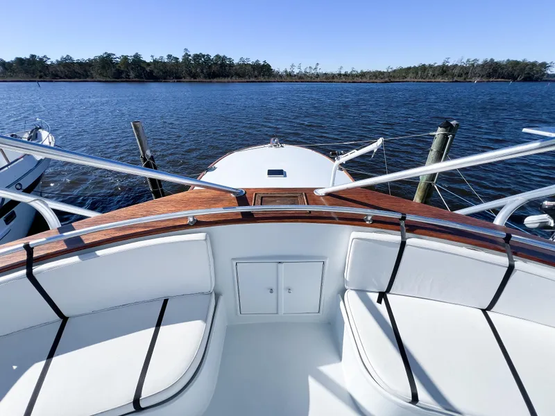 Slide: The Image of 1987 Buddy Davis 61 Convertible yacht bow with white seating, docked on a serene lake. - 32