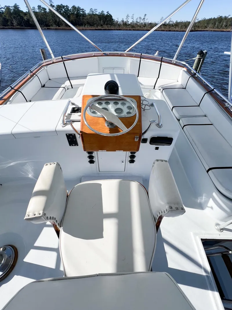 Slide: The Image of 1987 Buddy Davis 61 Convertible yacht helm with white seating and wooden dashboard, on calm water. - 33