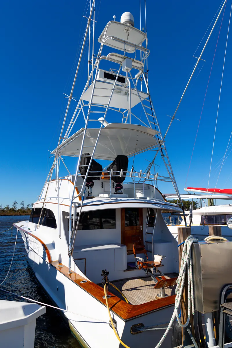 Slide: The Image of 1987 Buddy Davis 61 Convertible yacht with tall tower, docked under clear blue sky. - 6