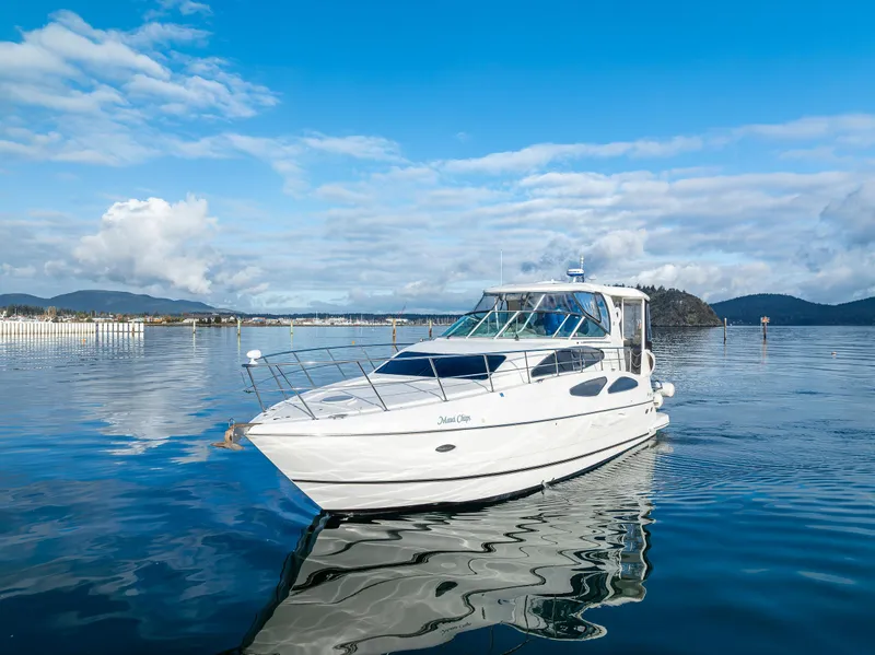 Slide: The Image of 2004 Cruisers Yachts 455 Express Motoryacht on serene water with scenic backdrop. - 48