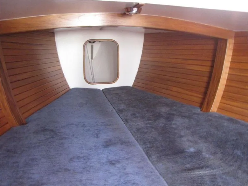 Slide: The Image of Interior cabin of 2025 Rustler 33 sailboat with wooden paneling and blue cushions. - 13