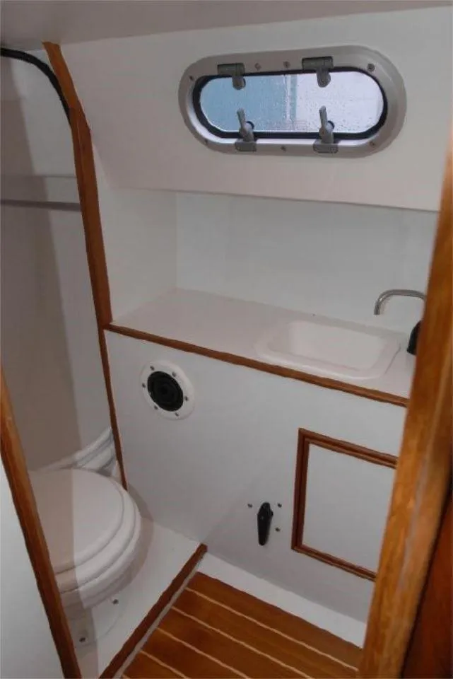 Slide: The Image of 2025 Rustler 33 yacht bathroom with wooden accents and porthole window. - 21
