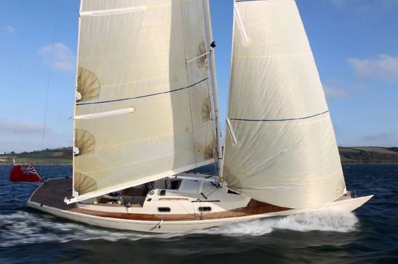 Slide: The Image of 2025 Rustler 33 sailboat gliding on water with full sails, clear sky background. - 3