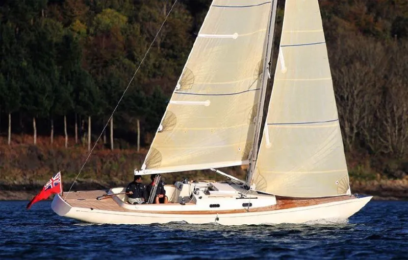 Slide: The Image of 2025 Rustler 33 sailboat cruising on a calm lake with forested background. - 4
