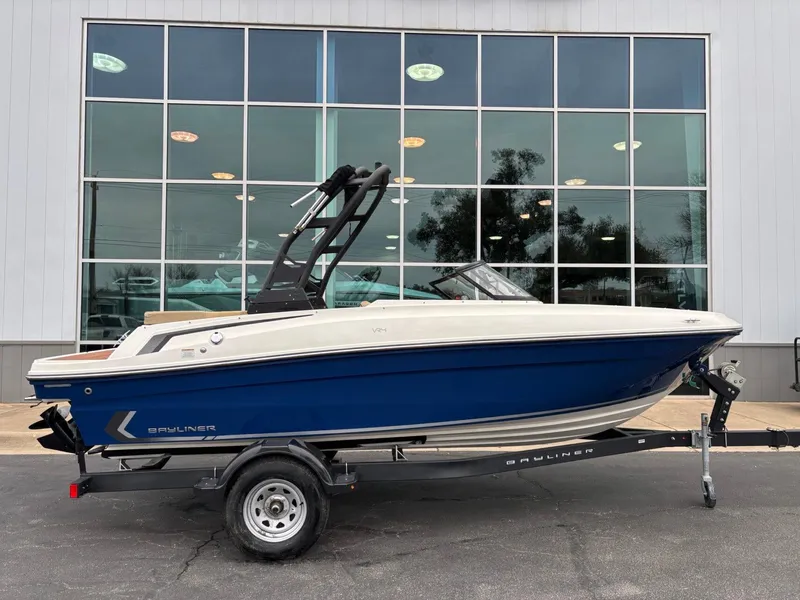 Slide: The Image of 2023 Bayliner VR4 boat on trailer, blue and white, parked outside a building. - 1
