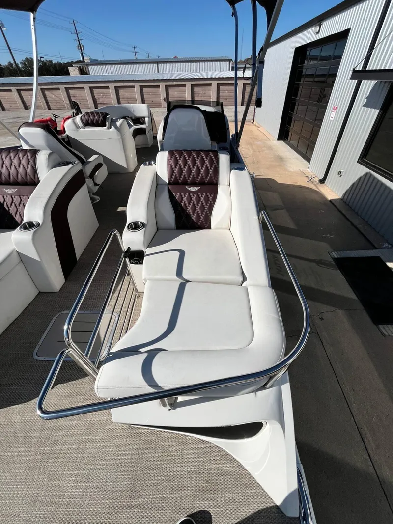 Slide: The Image of 2023 Bennington 23Q boat interior with white and brown seating, docked near a building. - 29
