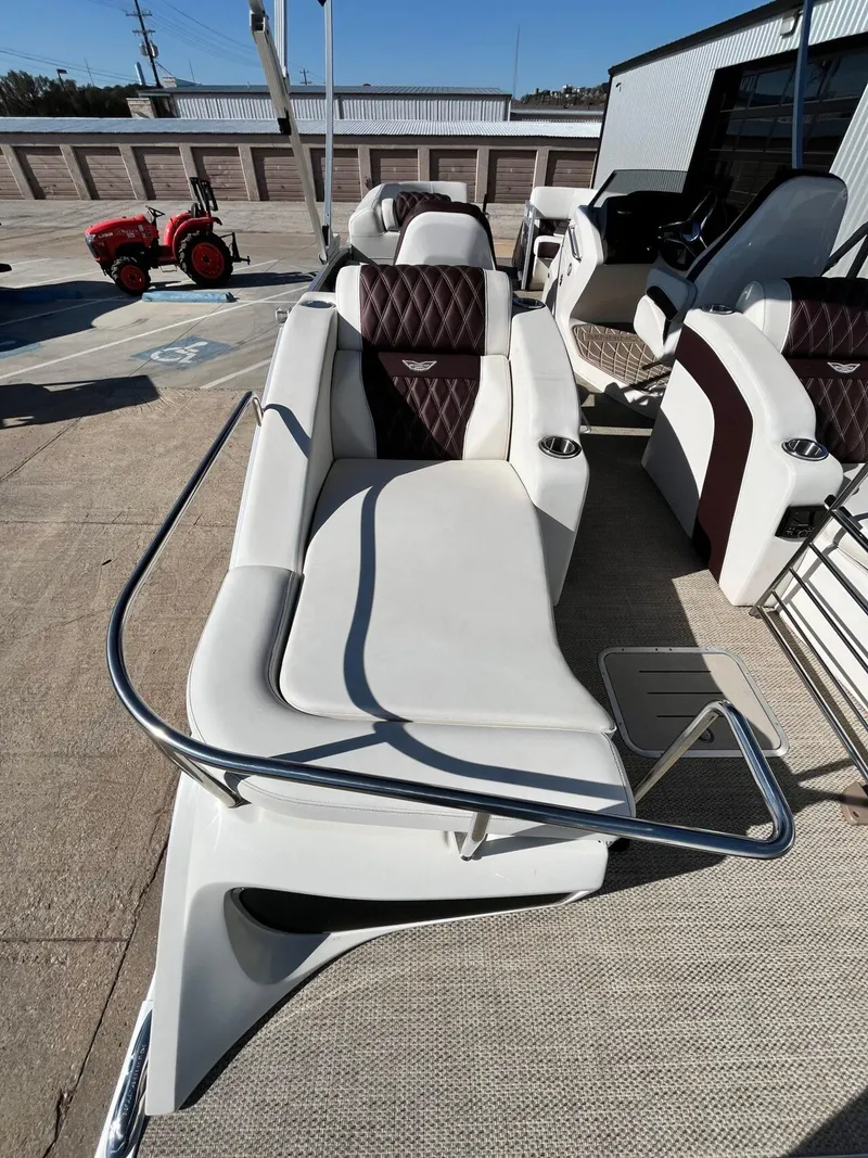 Slide: The Image of 2023 Bennington 23Q boat interior with white and brown seating, docked outdoors. - 36