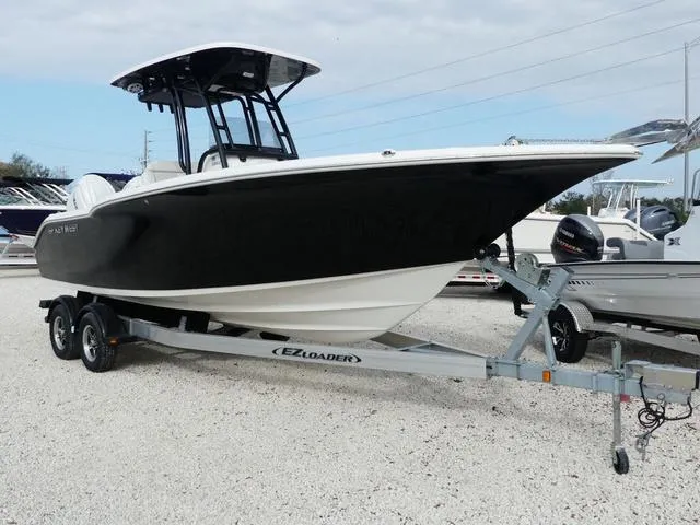 Slide: The Image of 2025 Key West 244 CC boat on trailer, front view, in a gravel lot. - 2