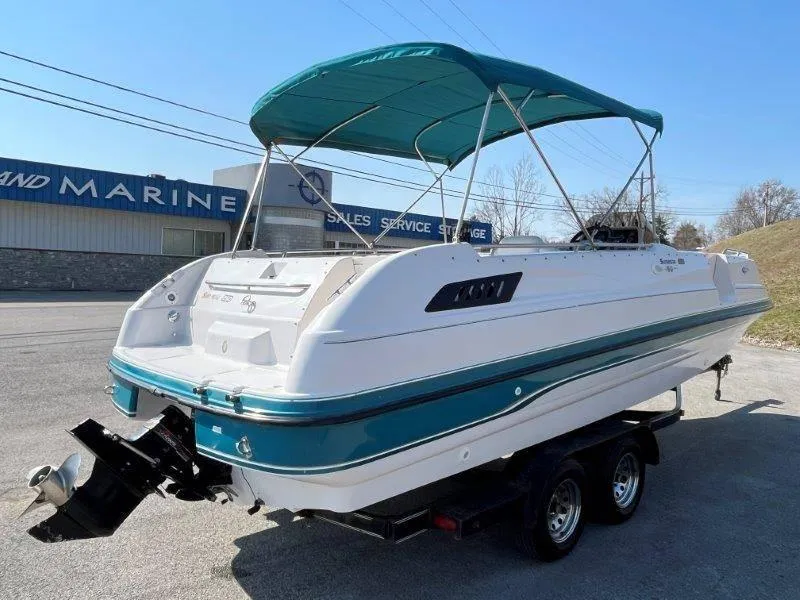 Slide: The Image of 1996 Chaparral Sunesta 250 boat with teal canopy on trailer, parked near marine shop. - 9